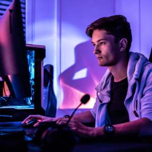 Portrait of persona: Krzysiek. He is sitting in a dark room in front of a computer.